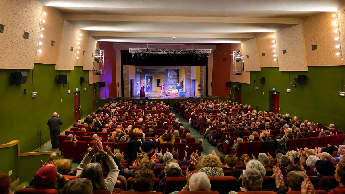 Pubblico al Cinema Teatro Arese durante uno spettacolo teatrale con platea gremita e palco illuminato